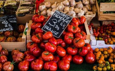 Tomates rouges et autres légumes sur un étal de marché avec paniers et prix affichés